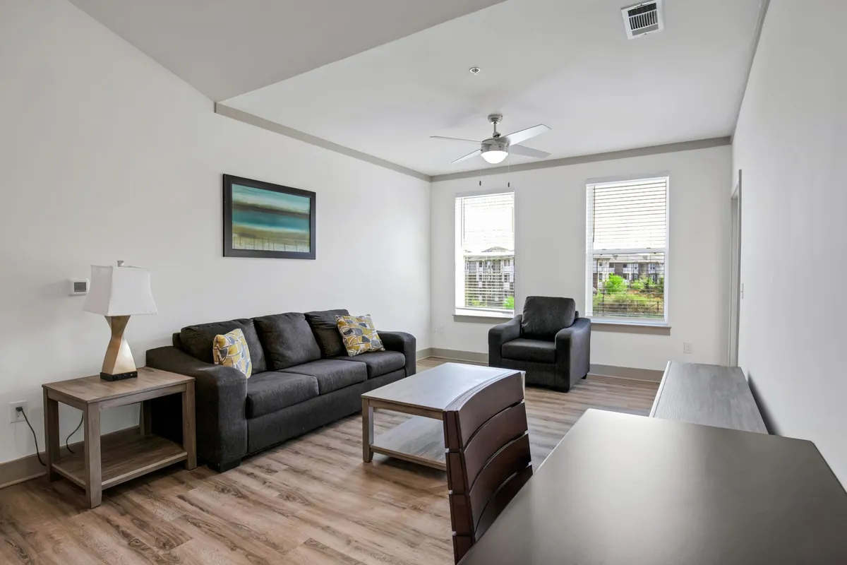 This inviting interior scene features a plush sofa, armchair, desk, lamp, and vibrant artwork, all arranged to foster relaxation, conversation, and productivity. The room is bright and welcoming, ideal for both casual gatherings and catching up on work with high-speed WiFi.