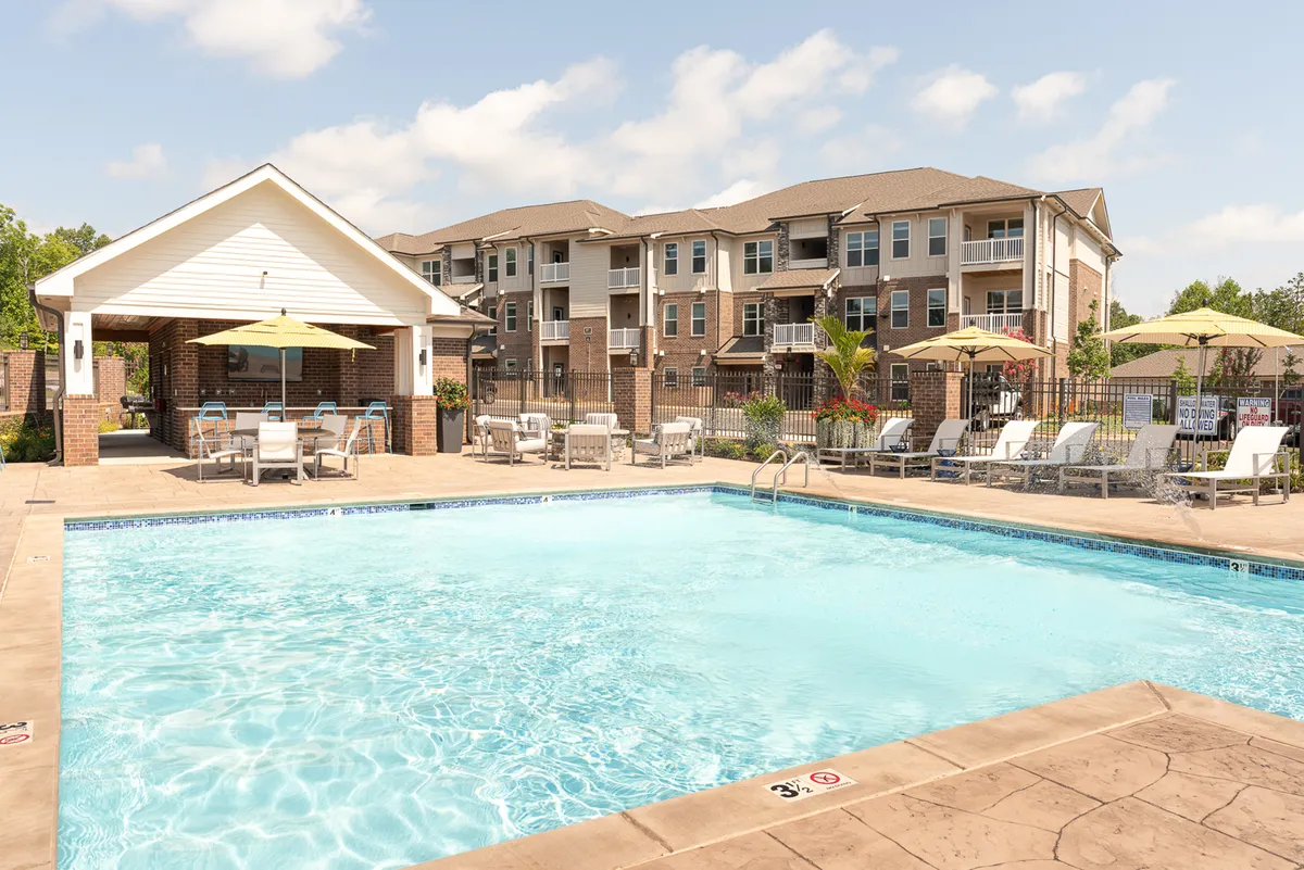 This image features a swimming pool area with cabanas, lounge chairs, and an apartment building in the background. The poolside setting is vibrant and inviting, ideal for family fun, outdoor gatherings, and relaxation after a day of exploring city attractions.