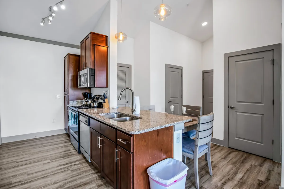 A contemporary kitchen with a granite countertop, stainless steel appliances, and a bar seating area. The open layout invites guests to gather while the cook prepares meals, with the countertop serving as a central hub for both cooking and casual dining.